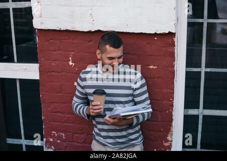 young cheerful businessman reading documents while holding coffee to go Stock Photo