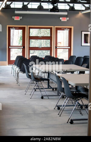 A large conference room is ready for the next group of people, with tables and chairs set up for a crowd Stock Photo