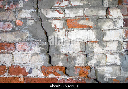 A crumbling brick wall is starting to break and weaken in this factory basement foundation Stock Photo