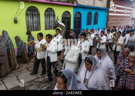 A band leads the Catholic procession of the Virgin of Carmen in San Pedro la Laguna, Guatemala.  Women in traditional Mayan dress with white mantillas Stock Photo
