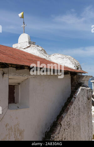 Rear view of the small, simple Catholic church in Santa Cruz la Laguna, Guatemala with outside stairs and a cross topped with a flag. Stock Photo