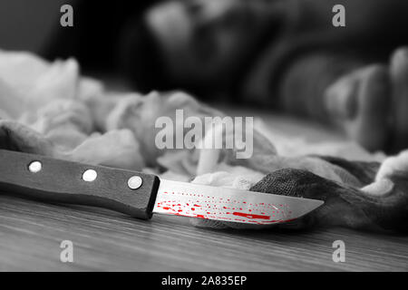 Bloodstained knife and dead man on floor. Suicide concept Stock Photo