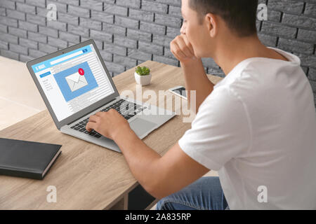 Young man with laptop checking an email at home Stock Photo