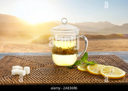 Cup of hot tea with lemon and sugar on table in desert Stock Photo