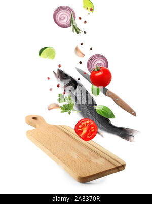 Wooden board and falling fish with ingredients on white background Stock Photo