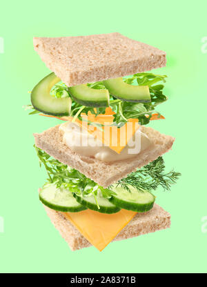 Tasty sandwich with flying ingredients on color background Stock Photo