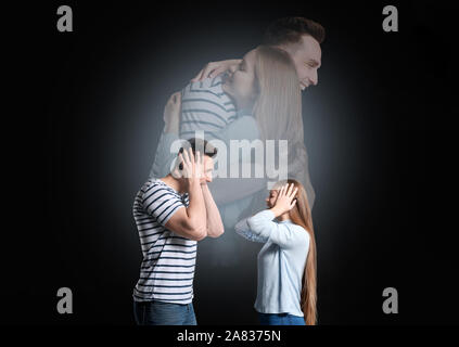 Quarreling young couple dreaming about making peace on dark background Stock Photo