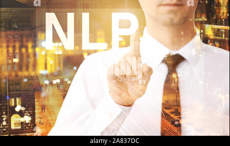 Double exposure of young businessman touching word NLP on virtual screen and illuminated city at night Stock Photo