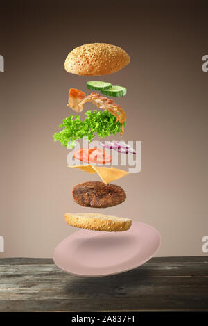 Tasty burger with flying ingredients on color background Stock Photo