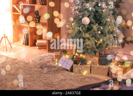 Beautiful Christmas gifts under fir tree in room Stock Photo