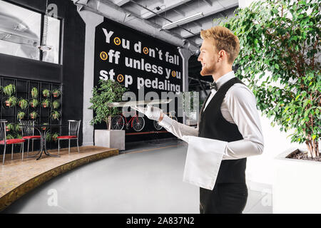 Handsome waiter with empty tray in modern cafe Stock Photo