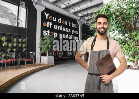 Handsome waiter with menu in modern cafe Stock Photo