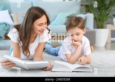 Little boy and his elder sister reading book at home Stock Photo