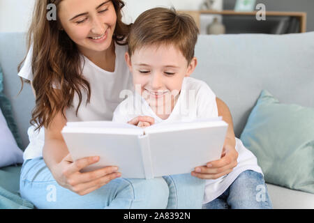 Little boy and his elder sister reading book at home Stock Photo