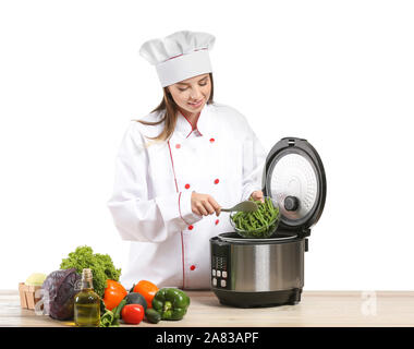 Female chef with modern multi cooker and products at table against white  background Stock Photo - Alamy