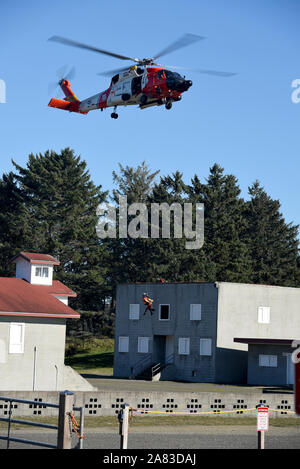 Petty Officer 3rd Class Bryan Evans, an aviation survival technician at Coast Guard Sector Columbia River, is lowered from an MH-60 Jayhawk helicopter to the open window of a building at the Camp Rilea Military Operations in Urban Terrain Village in Warrenton, Ore., Nov. 1, 2019. This urban search and rescue training evolution was conducted in conjunction with members of Aviation Training Center Mobile. (U.S. Coast Guard photo by Petty Officer 3rd Class Trevor Lilburn)