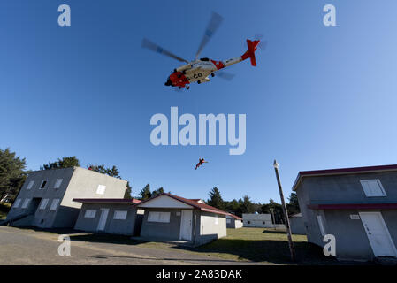 Petty Officer 3rd Class Bryan Evans, an aviation survival technician at Coast Guard Sector Columbia River, is lowered from an MH-60 Jayhawk helicopter to the roof of a simulated single story house at the Camp Rilea Military Operations in Urban Terrain Village in Warrenton, Ore., Nov. 1, 2019. This training was designed to meet the needs of aircrews in urban search and rescue operations, following feedback from members responding to major natural disasters in the past. (U.S. Coast Guard photo by Petty Officer 3rd Class Trevor Lilburn)