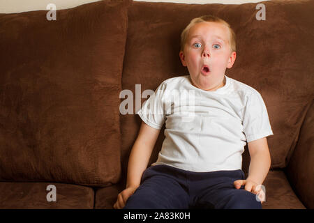 Kind on a couch making a funny surprised face