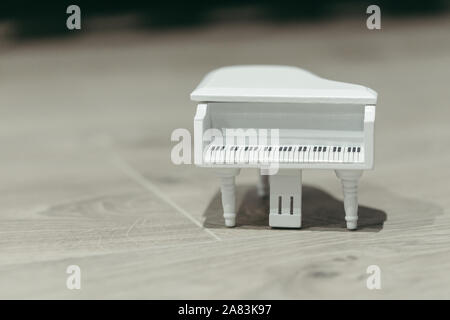 Tiny white toy piano music macro still isolated on a wooden background Stock Photo