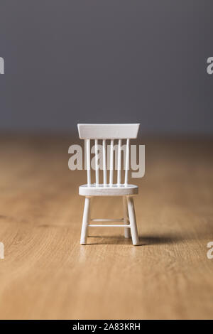 Tiny empty wooden white chair close up still on a wooden background Stock  Photo - Alamy