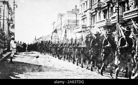 American troops in Vladivostok parading before the building occupied by the staff of the Czecho-Slovaks. Japanese marines are standing at attention as they march by. Siberia, August 1918. Stock Photo
