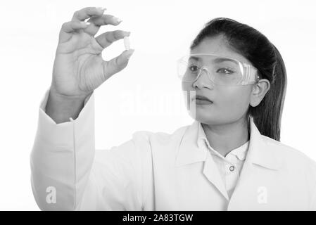 Close up of young fat Persian woman doctor looking at vitamin tablet while wearing protective glasses Stock Photo