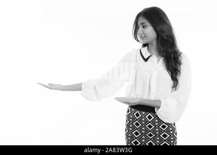 Profile view of young happy Persian businesswoman smiling while showing something Stock Photo