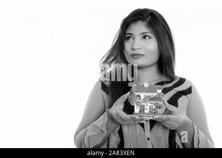 Close up of young fat Persian businesswoman thinking while holding house figurine Stock Photo
