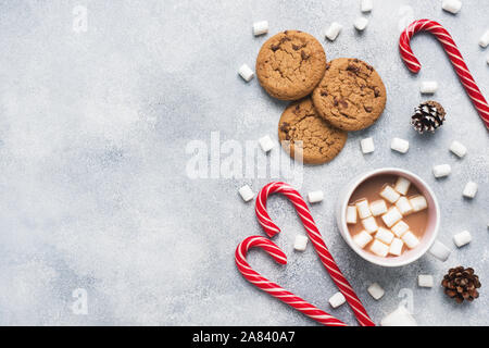 The chocolate chip cookie, Christmas cane caramel Cup cocoa and marshmallow cones Decorations on a gray background Copy space Frame. Stock Photo