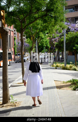 Nun walking down the street in a sunny day. Stock Photo