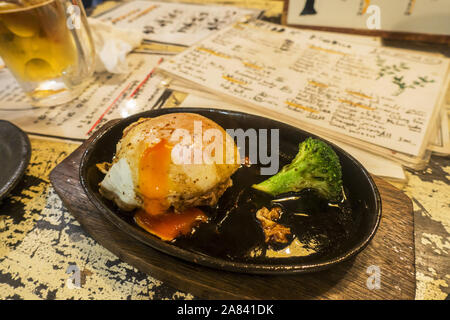 Osaka, Japan - November 2nd, 2019: Hamburger with fried egg on top served at a restaurant. Stock Photo