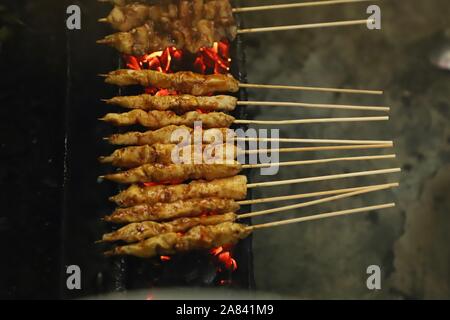 Indonesian Chicken Satay Being Grilled on Charcoal Flame Stock Photo