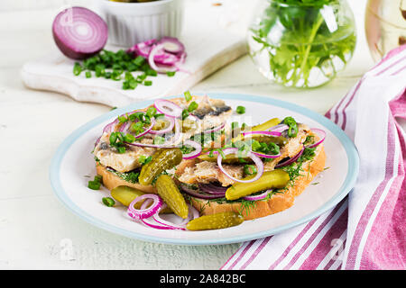 Traditional Dutch sandwich with herring and pickles cucumbers on white table. Smorrebrod. Stock Photo