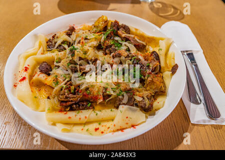 Traditional Kazakhstan Beshbarmak with Flat Noodles Lamb Meat Chopped Onions and Spices on a White Plate Stock Photo