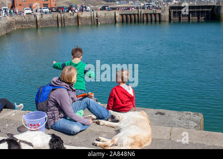 Two boys crabbing on the side of a harbour wall. Stock Photo