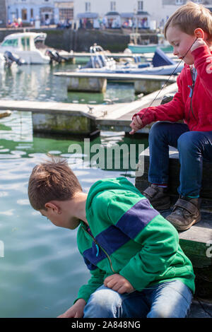 Two boys crabbing on the side of a harbour wall. Stock Photo