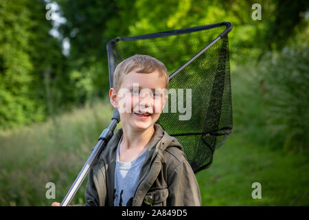 A young boy holding a fishing net over his shoulder. Stock Photo