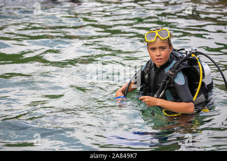 A young boy wearing full scuba diving outfit in the water. Stock Photo