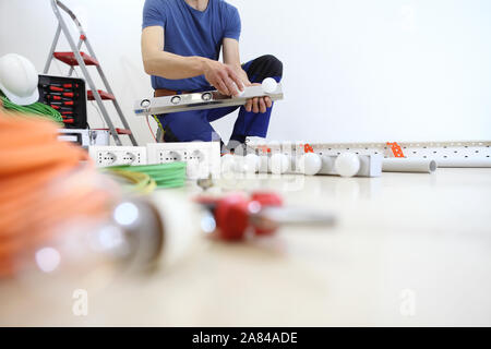electrician at work with tools, puts the bulbs on a lamp at home, electric circuits, electrical wiring Stock Photo