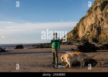 A young boy drinking hot chocolate on an empty beach, UK Stock Photo