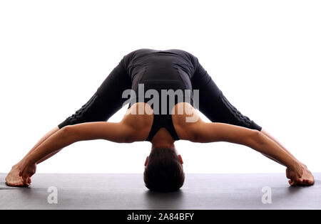 Yoga girl doing wide leg forward fold at gym. Woman stretching legs muscles  doing Prasarita Padottanasana training stretches on exercise mat in Stock  Photo - Alamy