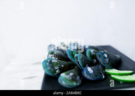 Exotic mussels on black square plate in white background. Stock Photo