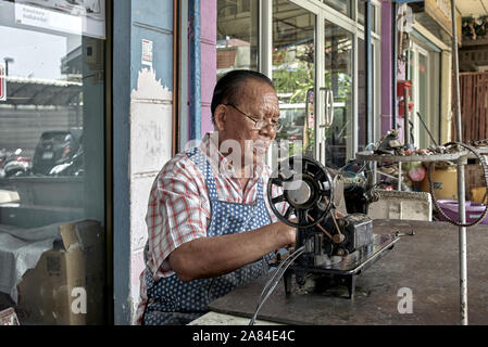 Repair man servicing vintage Singer sewing machine. Thailand Southeast Asia Stock Photo