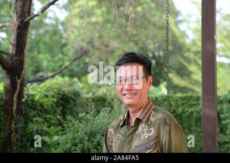 Portrait of an Asian Chinese successful businessman in formal traditional batik shirt, smiling at the camera. Confident. Stock Photo