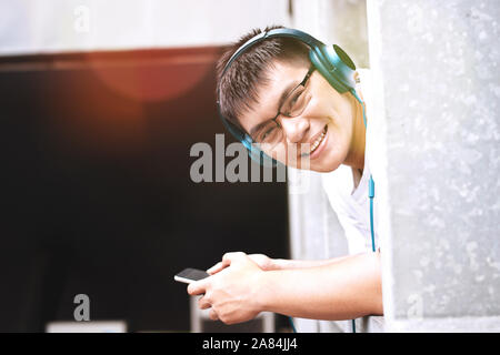 Young cute handsome men smiling and listening to music with smartphone and headphone Stock Photo
