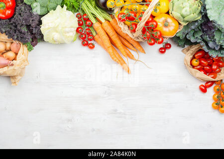 Top view of vegetables in paper bags and wicker basket on white wooden table, copy space, selective focus Stock Photo