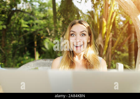 crazy woman with laptop looking at camera, sunshine green palms in Thailand Phuket while travel Stock Photo