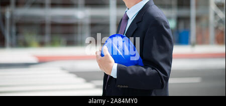 Detail of an architect site manager holding his hat in front of construction site Stock Photo