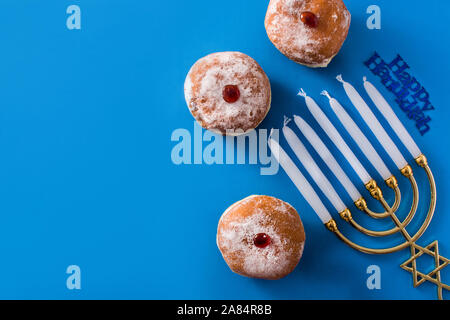 Jewish Hanukkah menorah and sufganiyot donuts on blue background. Top view. Copy space Stock Photo