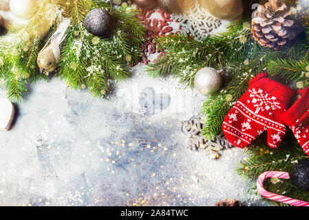 Christmas Frame made from Xmas Tree Branches, Baubles, Pine Cones, Candy Canes, Mittens and Snowflakes on the Grey Background, Top View, Flat lay, Space for text Stock Photo